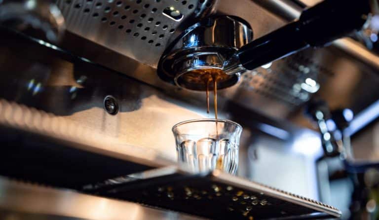 Close up of a coffee machine filtering coffee into espresso cup