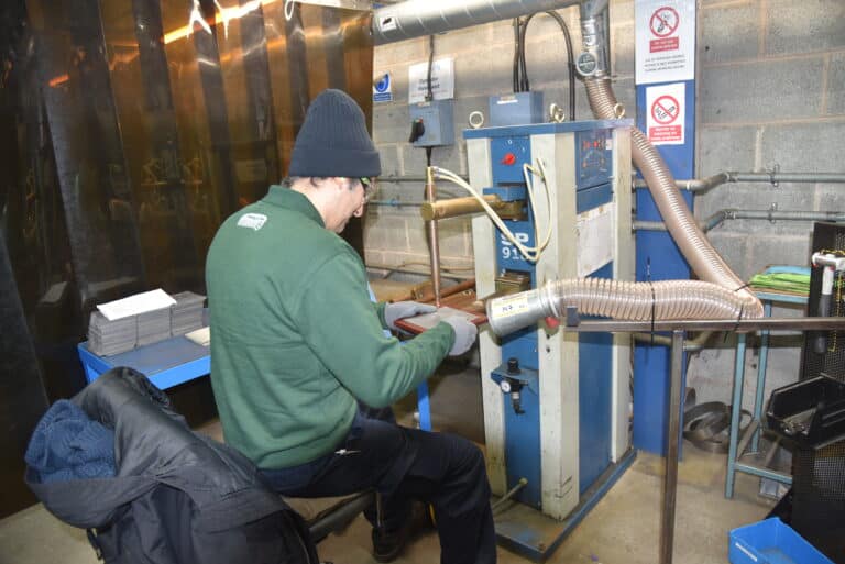 engineer welding a perforated metal disc and mesh metal disc together